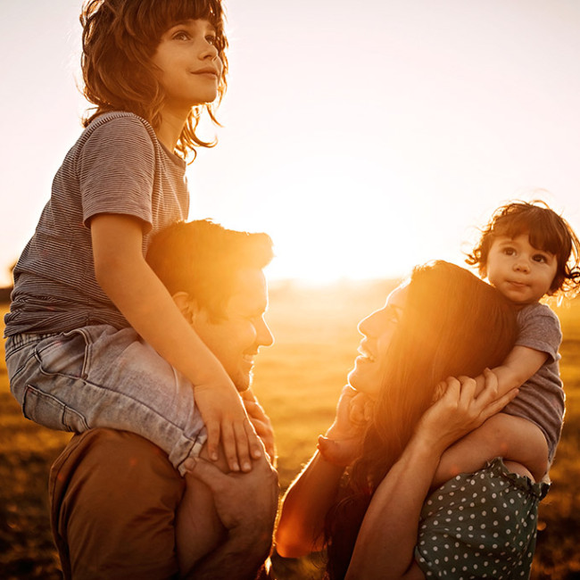 genitori con bambini in spalle al tramonto