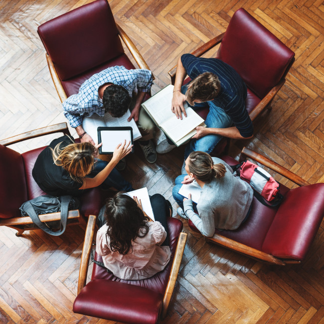 Cinque persone sedute in cerchio collaborano e consultano documenti e tablet in un ufficio moderno, rappresentando il modello di governance inclusiva e sostenibile del Gruppo